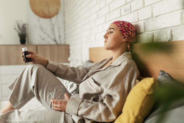 Young woman with cancer taking the pills, cancer awareness concept.