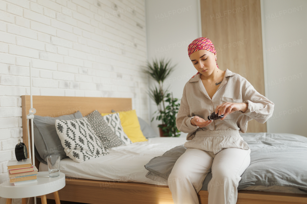 Young woman with cancer taking the pills, cancer awareness concept.