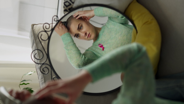 Young woman shaving her hair before chemotherapy. Vertical footage.