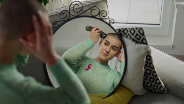 Young woman shaving her hair before chemotherapy.