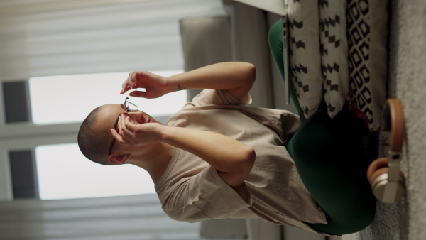 Young woman with cancer working on laptop in the apartment. Vertical footage.