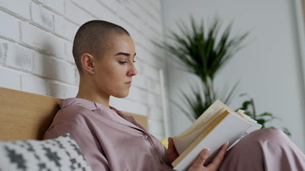 Young woman with cancer reading a book, cancer awareness concept.