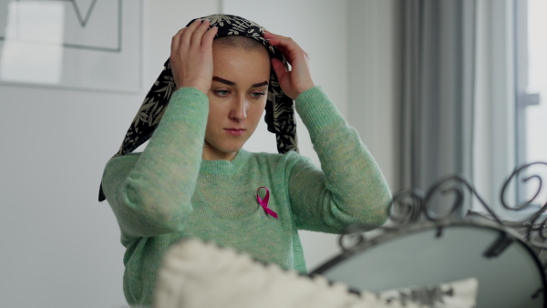 Beauty routine of a young woman with cancer, getting scarf on her head.