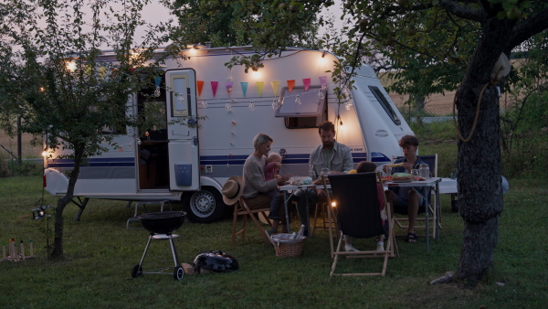 Family traveling in a caravan, having picnic diner. Parents with three kids during camping trip.