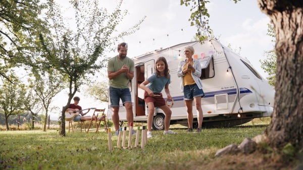 Parents playing outdoor games with daughter, having fun. Family traveling in a caravan, camping and exploring new places.