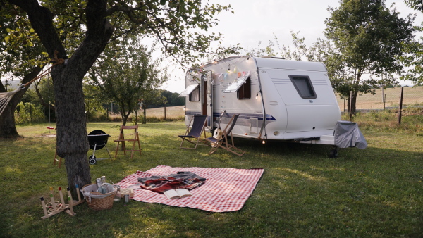 Traveling in a caravan, camping and exploring new places. Picnic diner in front of caravan.