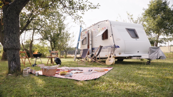 Traveling in a caravan, camping and exploring new places. Picnic diner in front of caravan.