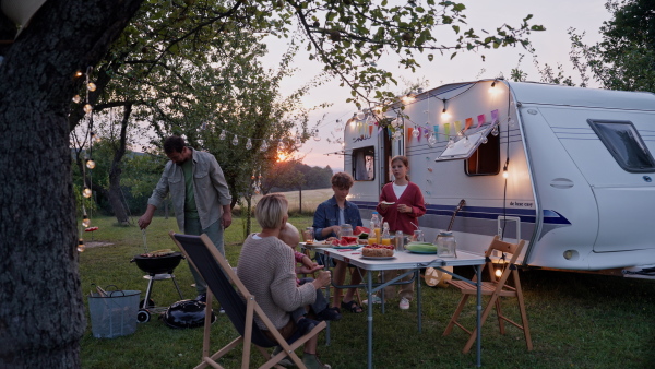 Family traveling in a caravan, having picnic diner. Parents with three kids during camping trip.