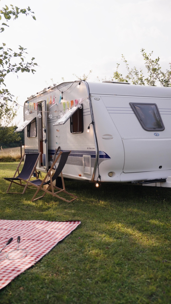 Traveling in a caravan, camping and exploring new places. Picnic diner in front of caravan.