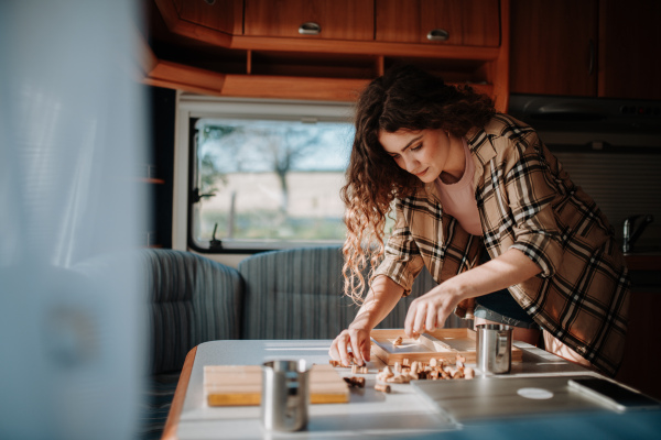 Woman putting away chess pieces after finished game. Camping trip in nature, sitting in caravan and playing chess.