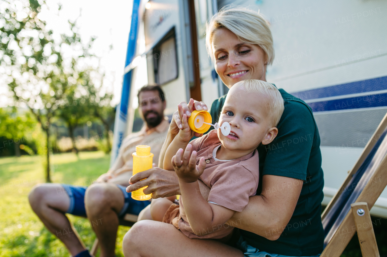 Portrait of family with small toddler on low-cost camping trip with caravan. Family roadtrip in caravan.