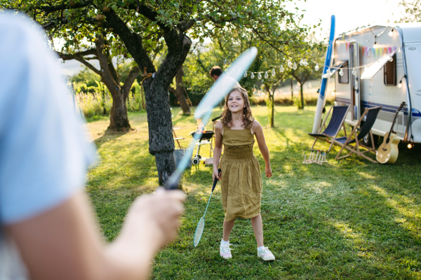 Siblings playing badminton outside on the lawn in the garden. The girl is holding a racket.