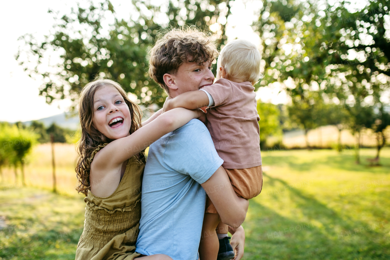 Three siblings are playing outdoor, having fun during warm summer evening.