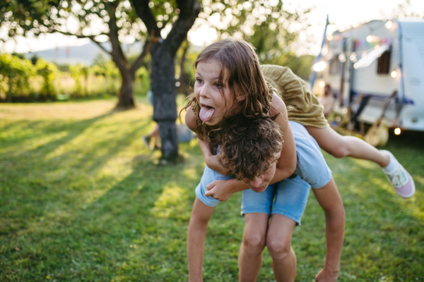 Two siblings are playing outdoor, having fun during warm summer evening.