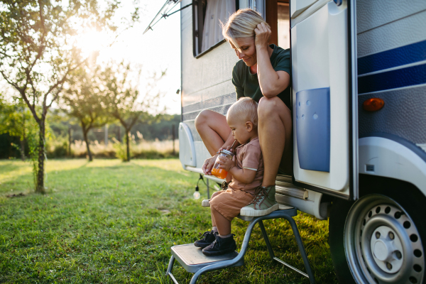 Portrait of single mother and toddler boy in caravan during their camping trip. Budget traveling.