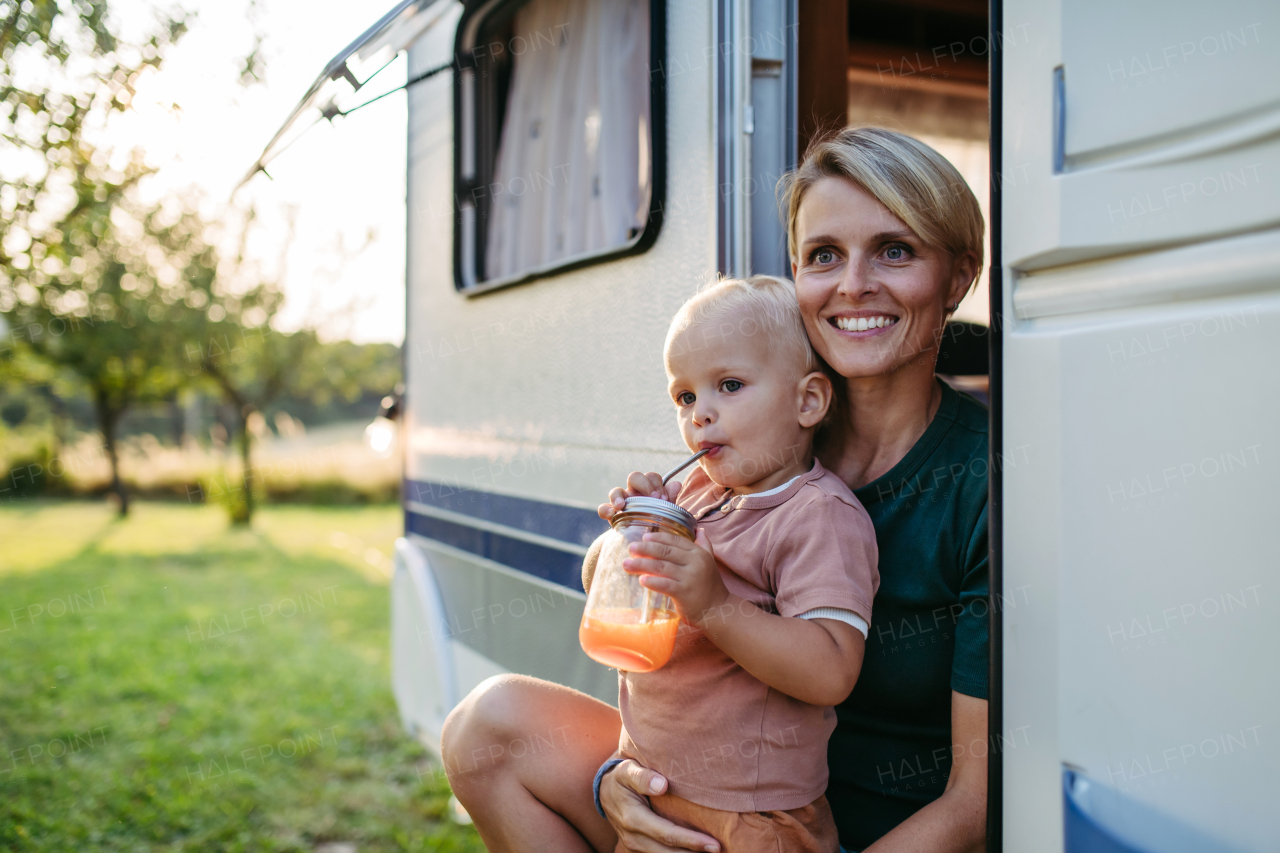 Portrait of single mother and toddler boy in caravan during their camping trip. Budget traveling.