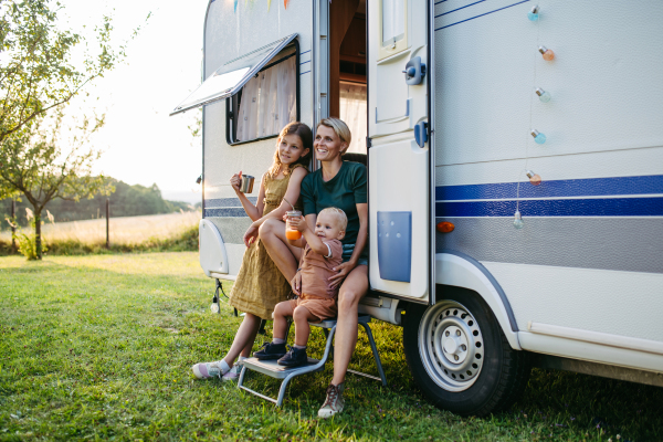 Portrait of single mother and kids in caravan during their camping trip. Budget traveling.