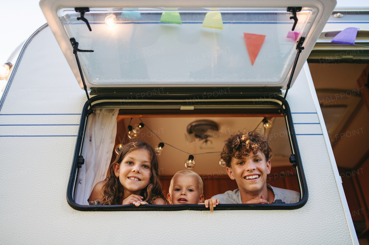 Siblings are standing in the caravan, looking out the window