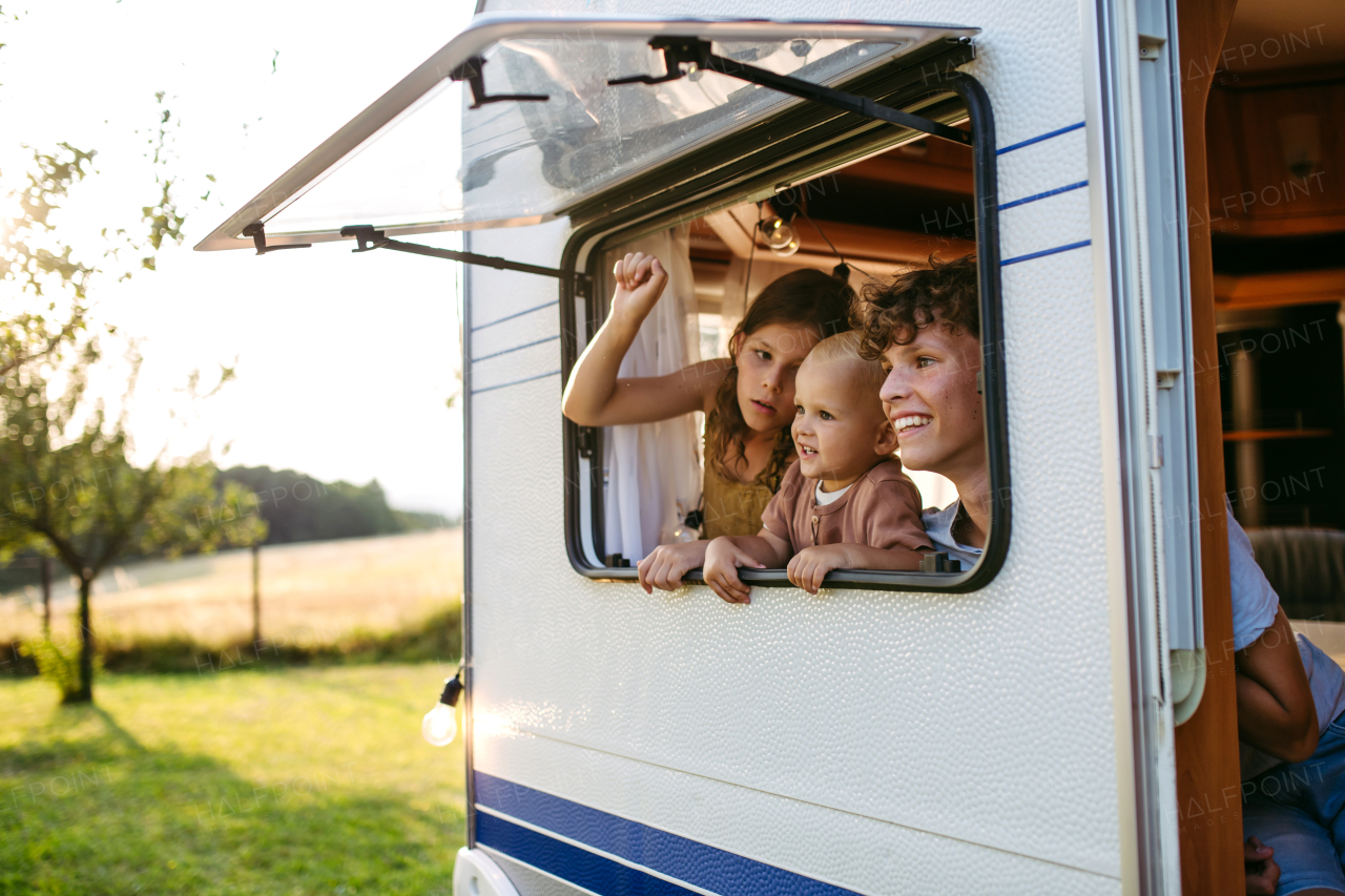 Siblings are standing in the caravan, looking out the window