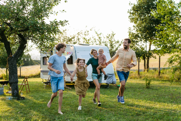 Portrait of family members walking in front of caravan and holding hands. Family roadtrip in caravan.