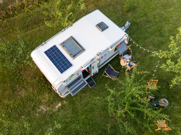 Top view of family in front of caravan during their camping trip. Family roadtrip in caravan.