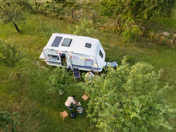 Top view of family in front of caravan during their camping trip. Family roadtrip in caravan.