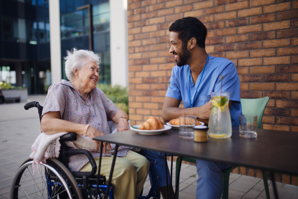 Caregiver having breakfast with his client at a cafe.