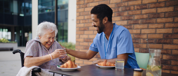 Caregiver having breakfast with his client at a cafe.