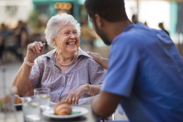 Caregiver having breakfast with his client at a cafe.