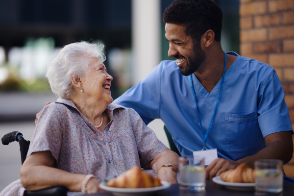 Caregiver having breakfast with his client at a cafe.