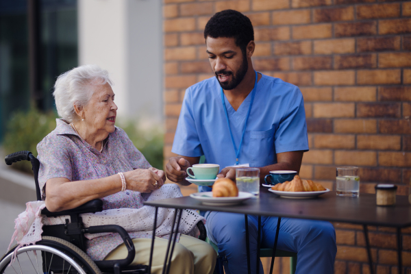 Caregiver having breakfast with his client at a cafe.