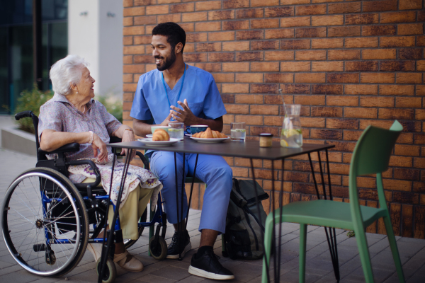 Caregiver having breakfast with his client at a cafe.