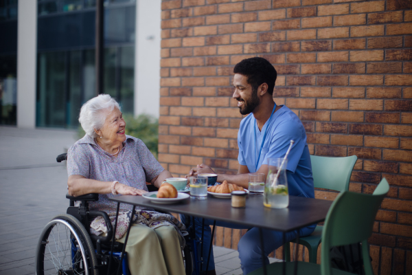 Caregiver having breakfast with his client at a cafe.