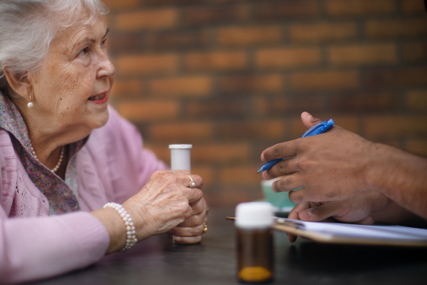 Clsoe -up of senior woman taking pills by a caregiver.