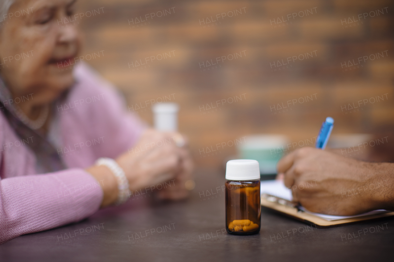 Clsoe -up of senior woman taking pills by a caregiver.