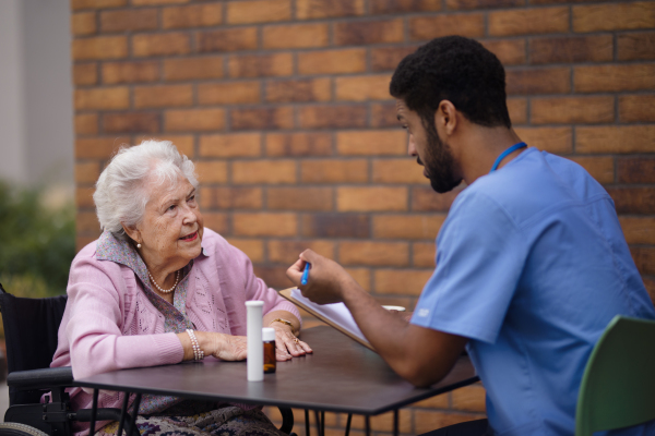 Caregiver explaning dosing pills to senior woman.