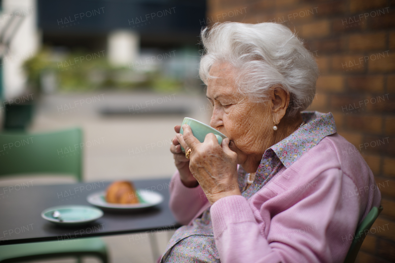 Happy senior woman enjoying cup of coffee and breakfast at city cafe.