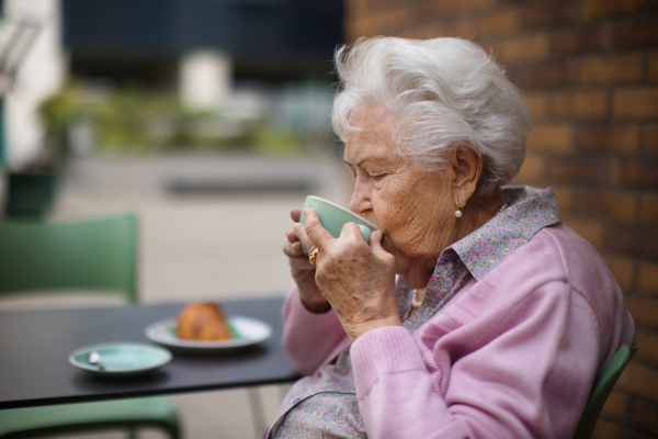 Happy senior woman enjoying cup of coffee and breakfast at city cafe.