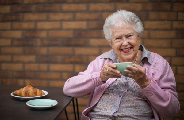 Happy senior woman enjoying breakfast at city cafe.