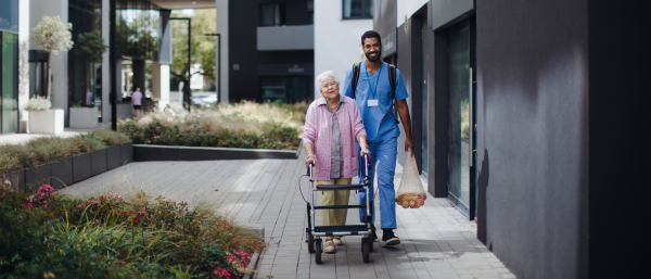 Happy caregiver caming back from grocery with senior woman client.