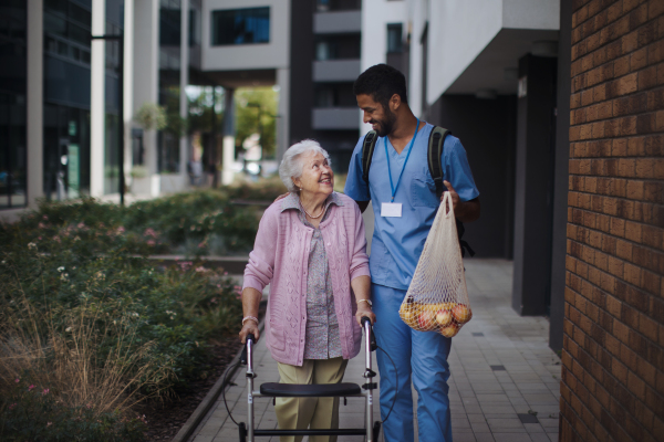 Happy caregiver caming back from grocery with senior woman client.