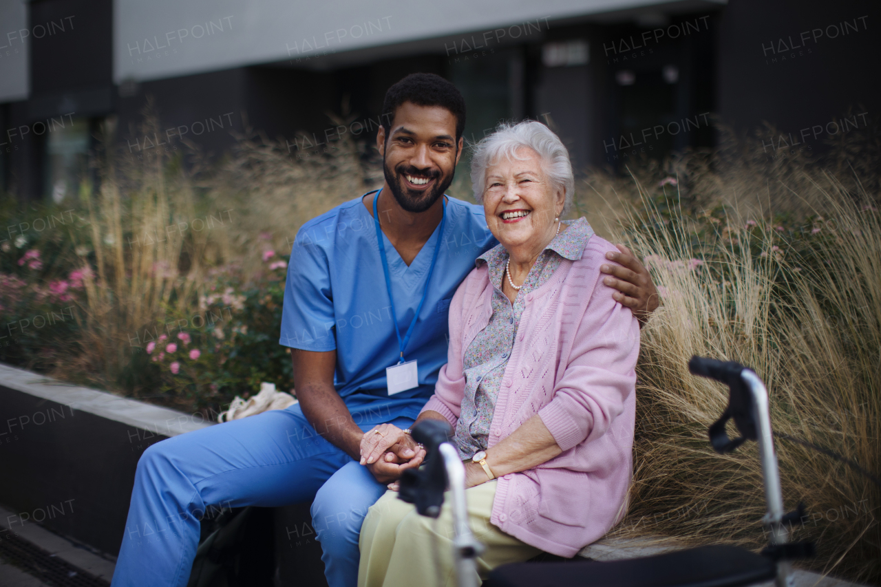 Happy senior woman sitting and talking with a medical assistant in front of nurishing home.