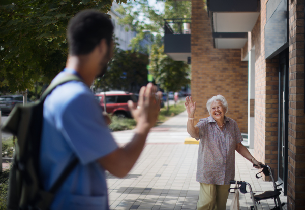 Caregiver saying goodbye his senior woman client at a nursing home.