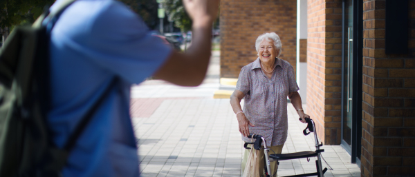 Caregiver saying goodbye his senior woman client at a nursing home.