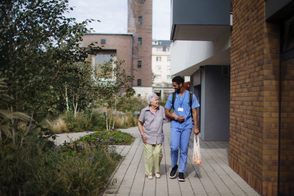 Happy caregiver caming back from grocery with senior woman client.