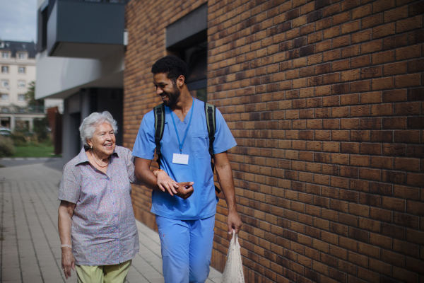 Happy caregiver caming back from grocery with senior woman client.