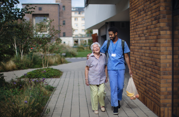 Happy caregiver caming back from grocery with senior woman client.