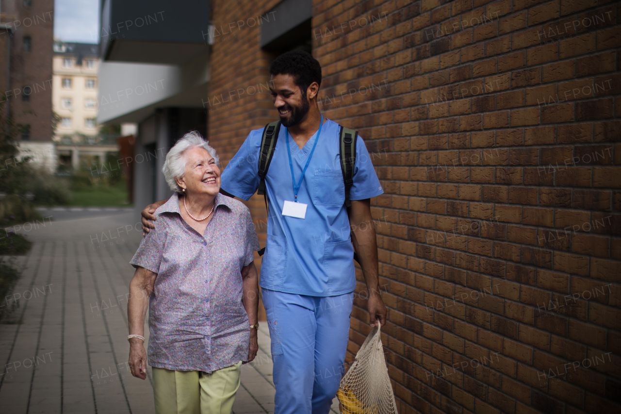 Happy caregiver caming back from grocery with senior woman client.