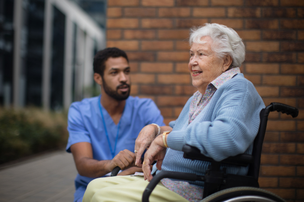 Happy senior woman at a wheelchair spending time outside with her assistant.