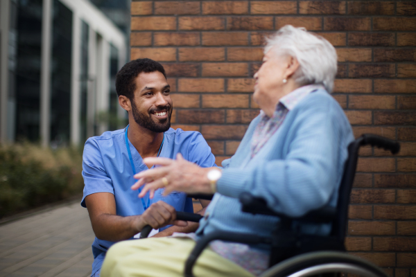 Happy senior woman at a wheelchair spending time outside with her assistant.